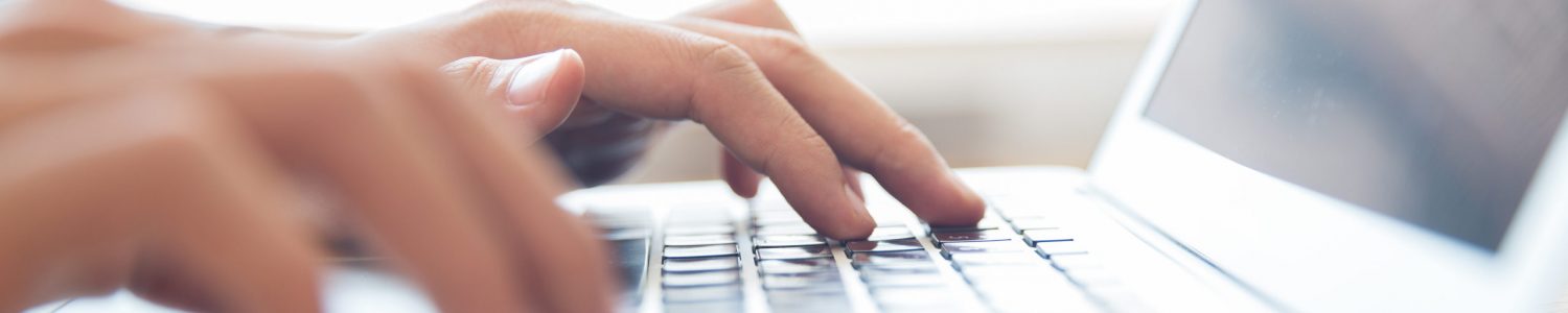 Close-up of male hands typing on laptop keyboard indoors. Businessman working in office or student browsing information